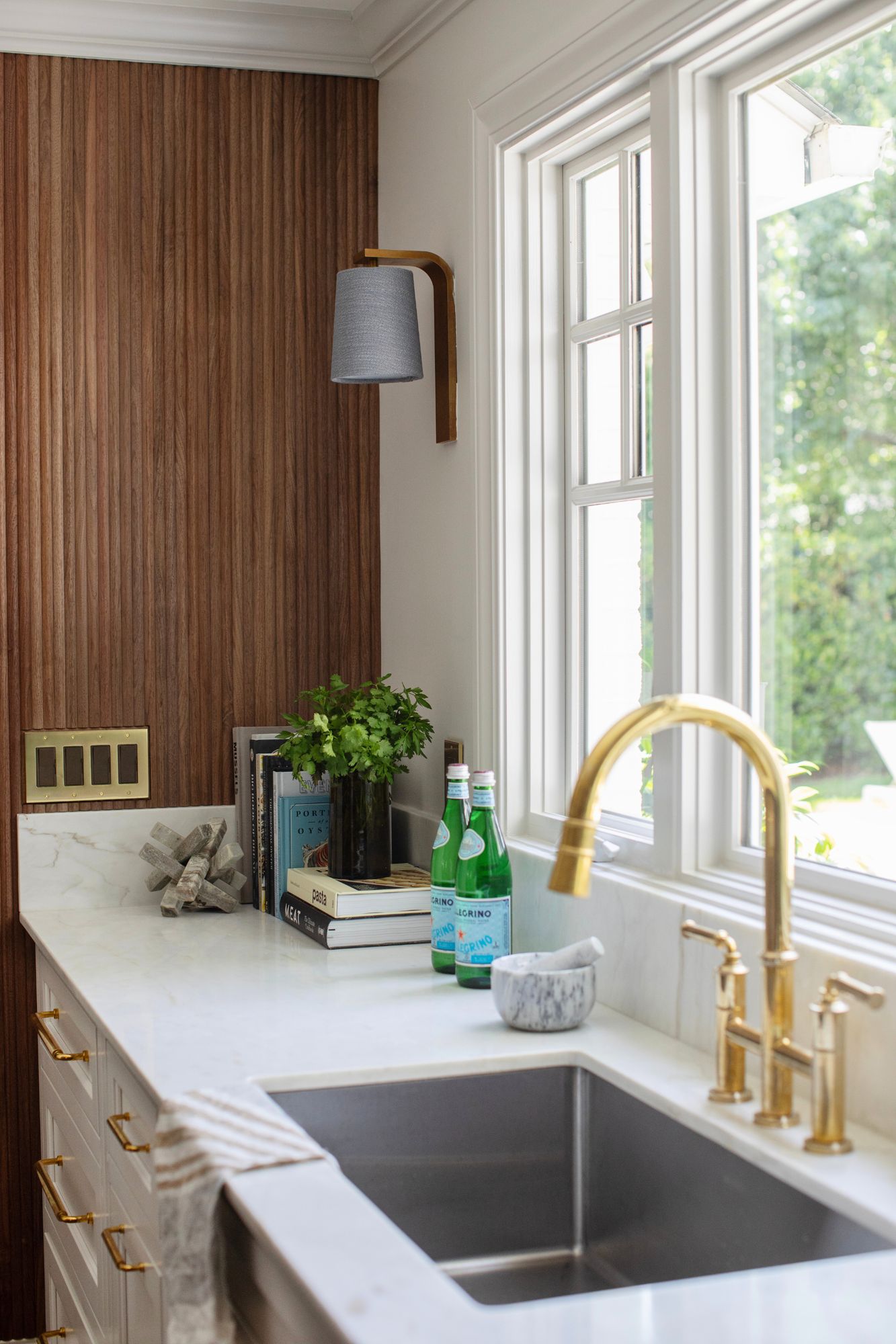 Kitchen sink with brass faucet under window